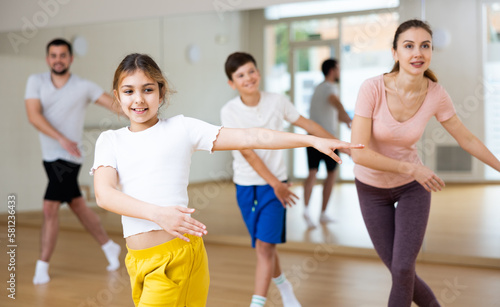Young girl exercising aerobic dance with her family in gym.