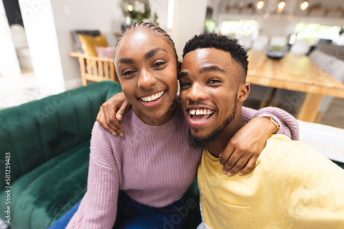 Wallpaper Mural Happy african american couple sitting on sofa and having video call in living room Torontodigital.ca