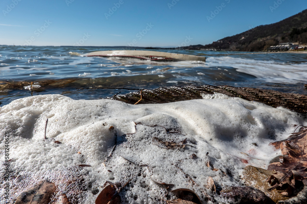 Tidal sea wavTidal sea waves with foam in the background is a sunken boat near the shore Tidal sea wavTidal sea waves with foam in the background is a sunken boat near the shore