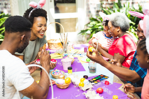 Happy african american family coloring easter eggs in garden