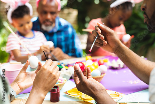 Happy african american family coloring easter eggs in garden