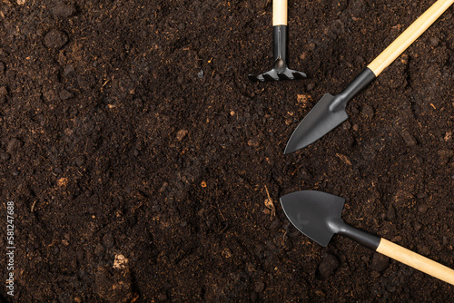 Garden tools on the background of the texture of fertile soil.Garden shovels and rakes. Top view. Flat lay. Concept of gardening or planting. Work in the spring garden.