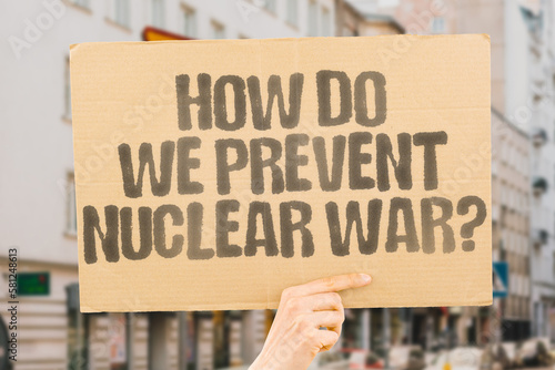 The question "How do we prevent nuclear war? " is drawn on a carton banner in men's hands. Conflict. Crisis. Threat. Missile. Bomb. Explosion. Destruction. Devastation. Radiation. Fallout. Defense