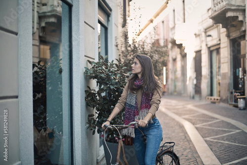 young woman on a bicycle looks at a shop window