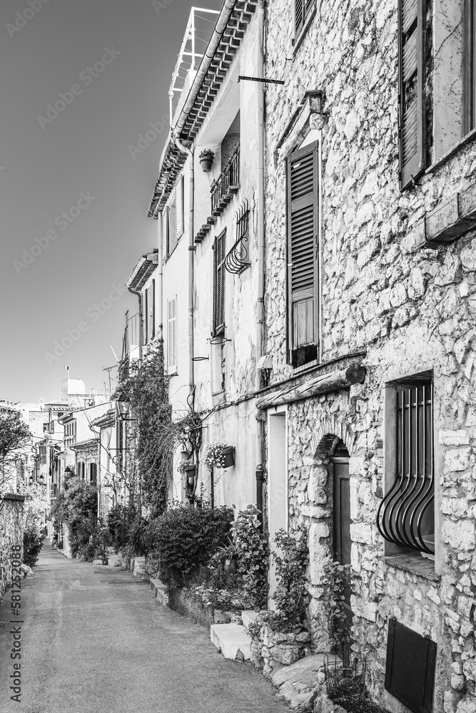 Narrow street with colorful houses in Antibes, Cote d'Azur, France in black and white