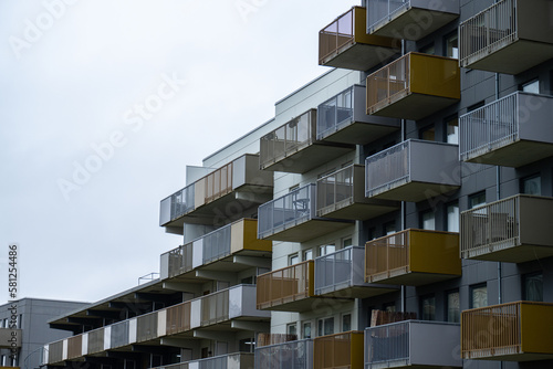 Grey tall apartment building with white and golden balconies.