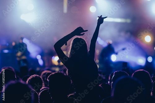 Silhouette of a woman with raised hands on a concert