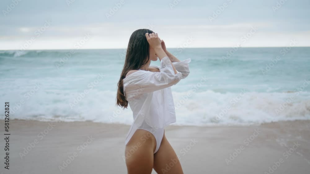 Girl walking gray seashore in front stormy foamy waves. Woman stepping beach Girl walking gray seashore in front stormy foamy waves. Woman stepping beach