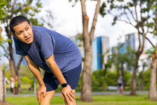 Portrait of Asian man in sportswear jogging exercise at public park in summer morning. Healthy guy athlete enjoy outdoor activity lifestyle sport training fitness running workout in the city.