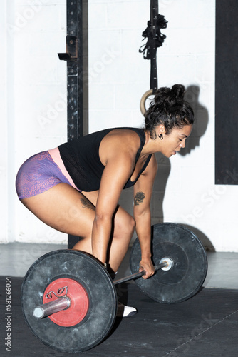 latin woman lifting weights in a gym