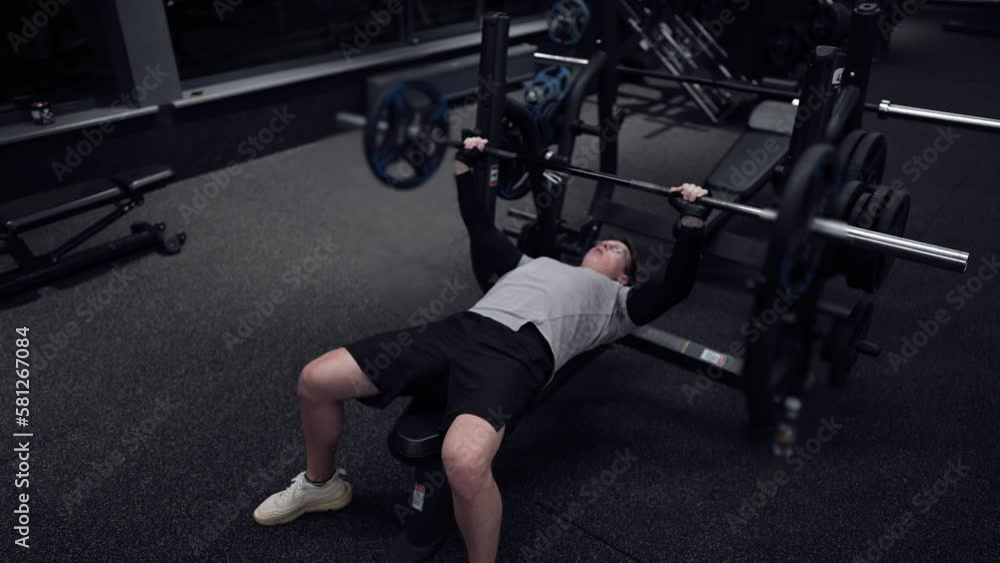 Fitness man trains in a modern gym and does bench press, barbell, weightlifting slow motion Fitness man trains in a modern gym and does bench press, barbell, weightlifting slow motion