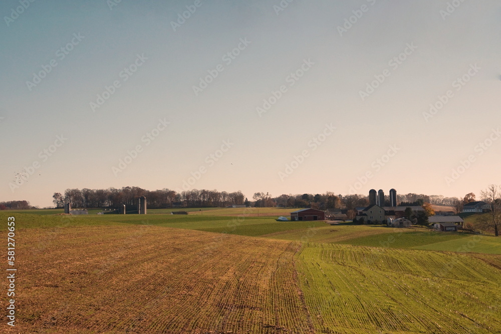 Farmscape, plowed fields, silos and buildings, blue sky