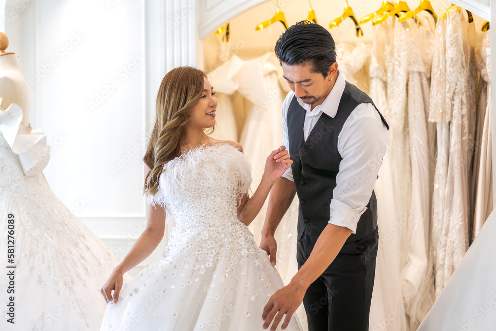 Fototapeta premium Portrait of smiling cheerful happy love asian couple fashion bride man and woman posing in white wedding dress for pre wedding hug together at wedding interior fashion studio
