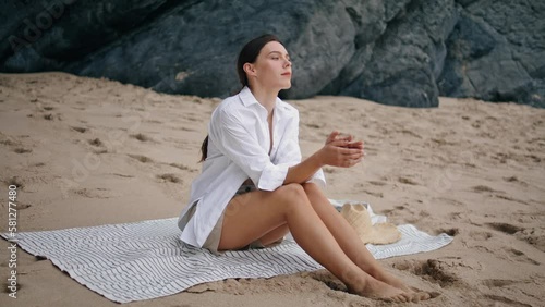 Woman sitting blanket beach looking on seascape. Calm girl relaxing at coverlet 