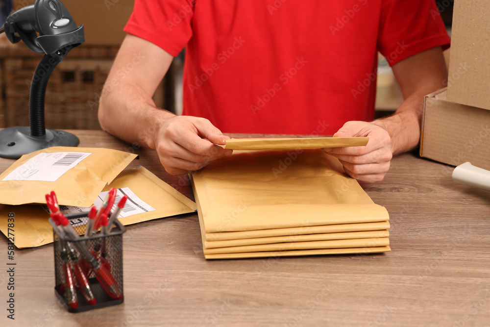 Post office worker with adhesive paper bags at counter indoors, closeup