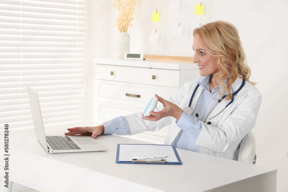 Doctor with laptop and pills consulting patient in clinic. Online medicine concept Doctor with laptop and pills consulting patient in clinic. Online medicine concept