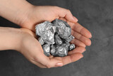 Woman with silver nuggets at grey table, closeup