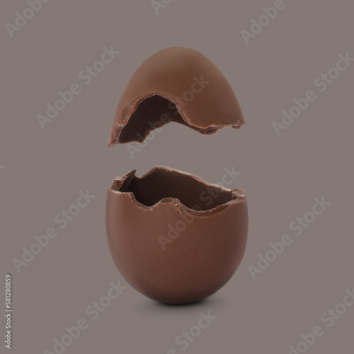 Broken milk chocolate egg on grey background
