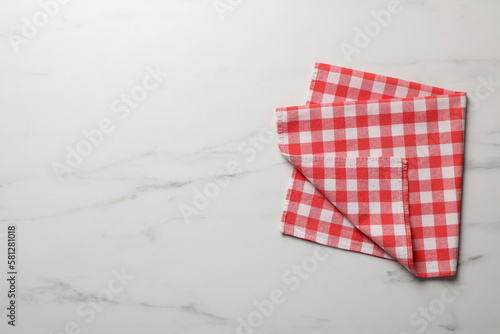Red checkered tablecloth on white marble table, top view. Space for text