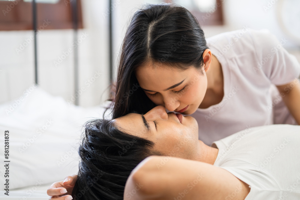 Asian wife kissing her husband while lying down sleep on bed in bedroom. Asian wife kissing her husband while lying down sleep on bed in bedroom.