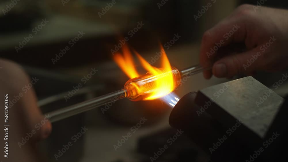 Glass blowing artist heating glass art piece in fire Glass blowing artist heating glass art piece in fire