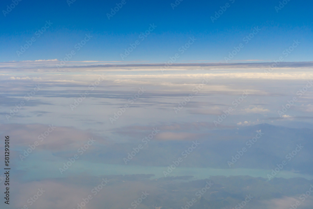 Airplane jet flying above clouds view with blue sky from the window in traveling and transportation concept. Nature landscape background.