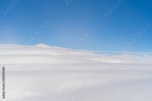 Airplane jet flying above clouds view with blue sky from the window in traveling and transportation concept. Nature landscape background.