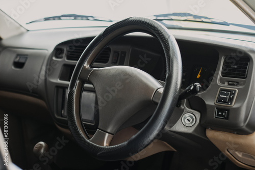 Black classic car interior. Steering wheel, speedometer, display and multimedia dashboard. Detail of car interior inside. Manual gear stick. © sidoe98