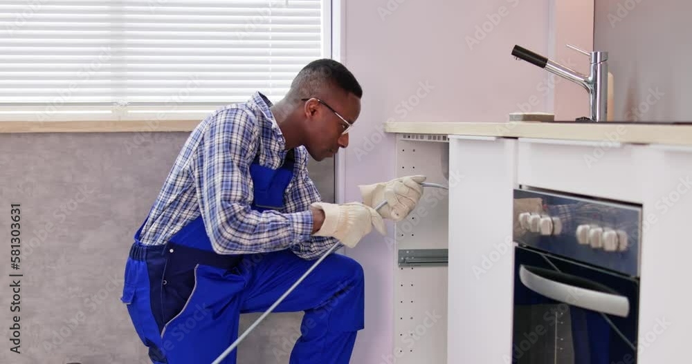 Young Male Plumber Cleaning Clogged Sink Pipe Young Male Plumber Cleaning Clogged Sink Pipe