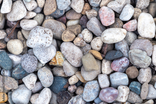 Close up background photograph of dry pea gravel stone or rock garden with rounded edges and muted white, blue, pink, brown and yellow colors.