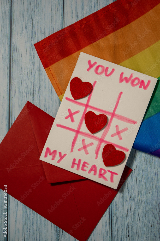 Handmade valentine with Text YOU WON MY HEART and tic tac toe game red envelope and LGBTQ flag. Gift idea with your own hands. Diversity equality 