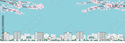 桜の花びらが舞う青空と家・マンション・お店・ビルが連なる街並みのバナー背景（青）　Banner background of a blue sky with dancing cherry petals and a cityscape of houses, apartments, stores, and buildings (blue)