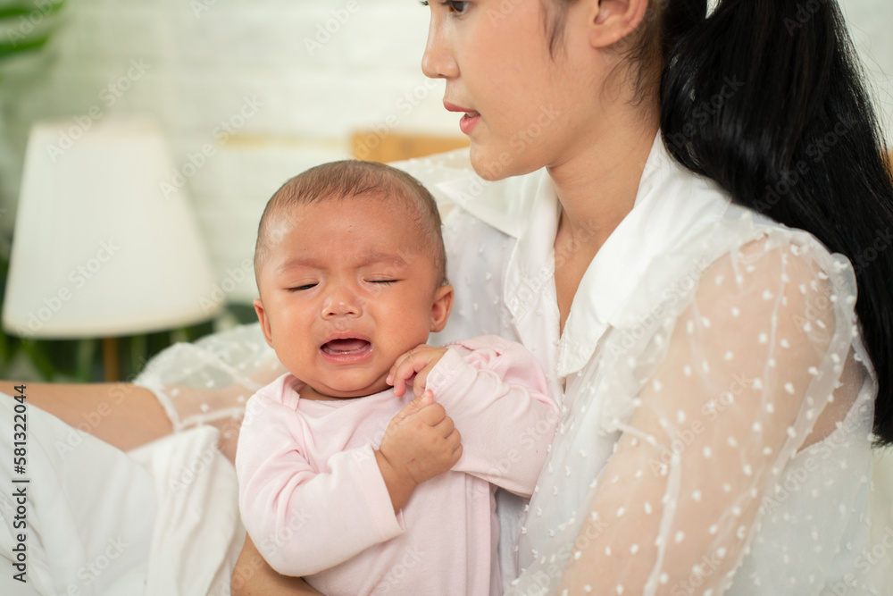 Loving Asian Mom carying of her newborn baby at home in the bedroom. happy family. mother playing with her baby in the bedroom. Mother hugging her little 2 months old Girl. Loving Asian Mom carying of her newborn baby at home in the bedroom. happy family. mother playing with her baby in the bedroom. Mother hugging her little 2 months old Girl.
