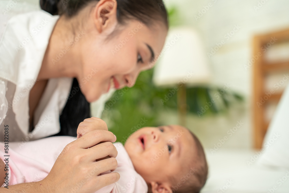Loving Asian Mom carying of her newborn baby at home in the bedroom. happy family. mother playing with her baby in the bedroom. Mother hugging her little 2 months old Girl. Loving Asian Mom carying of her newborn baby at home in the bedroom. happy family. mother playing with her baby in the bedroom. Mother hugging her little 2 months old Girl.