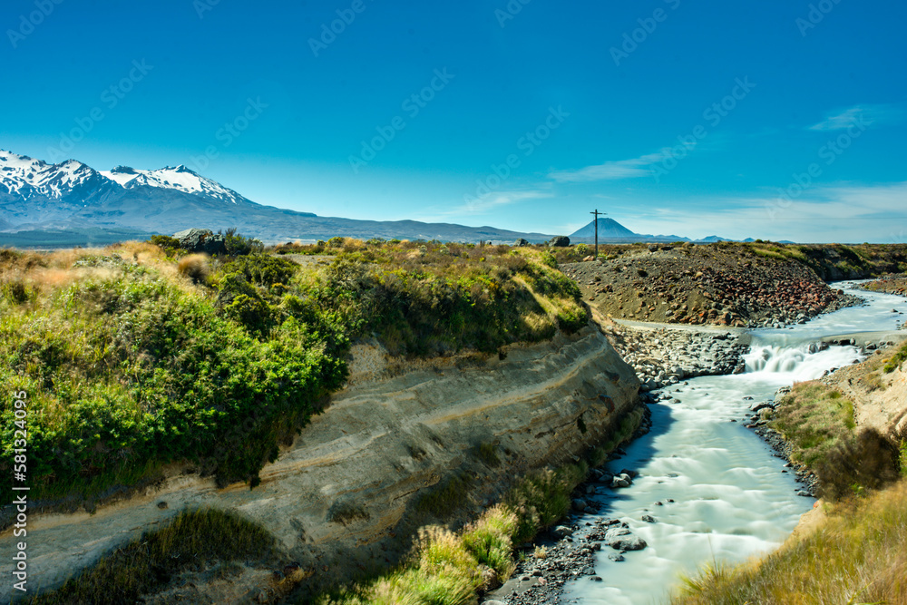 River rapids flowing through the volcanic terrain with volcanos in the background