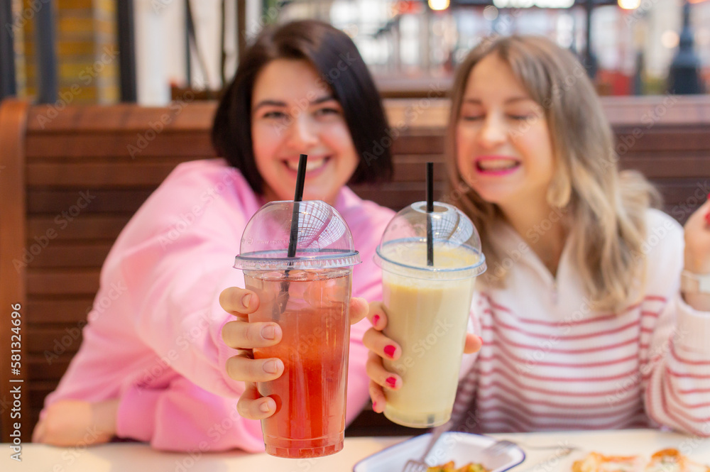 Two women friends drinking juice, smiling and talking in cafe Two women friends drinking juice, smiling and talking in cafe