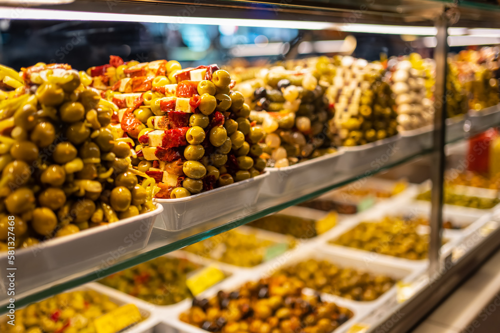 Naklejka premium Counter of a market with piles of food, olives and pickles in a colorful exhibition, Mercado San Miguel, Madrid.