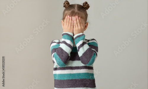 Foto Child placing hands across face to express embarrassment dismay or fear on grey