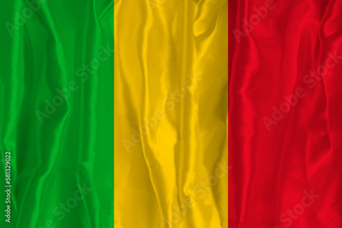 The flag of Mali on a silk background is a great national symbol. Texture of fabrics The official state symbol of the country