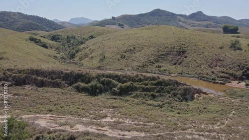 Going up behind the pasture on the hill shows a small lagoon with muddy water like a hidden swamp with mountains on the horizon photo