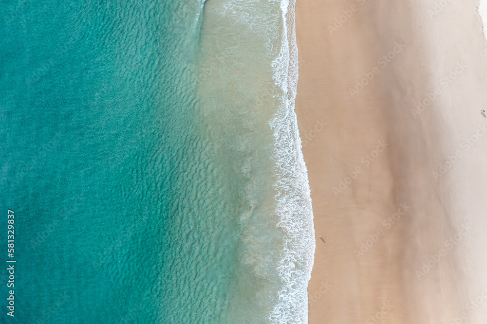 Aerial view of a beach with stunning clear water and warm white sand in a holiday paradise near the Pacific Ocean