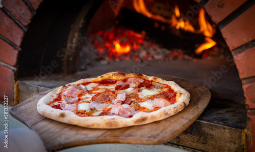 Quadro su tela Chef placing pizza in brick oven
