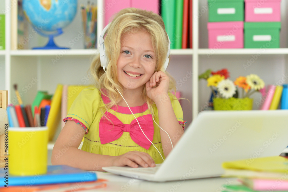 girl in headphones ding with laptop sitting at desk girl in headphones ding with laptop sitting at desk