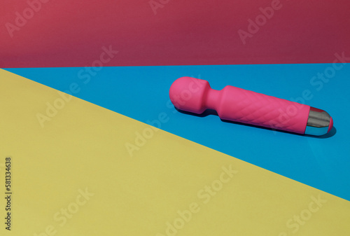 Pink dildo vibrator for satisfaction on colored background with shadows. Sex toy for adult