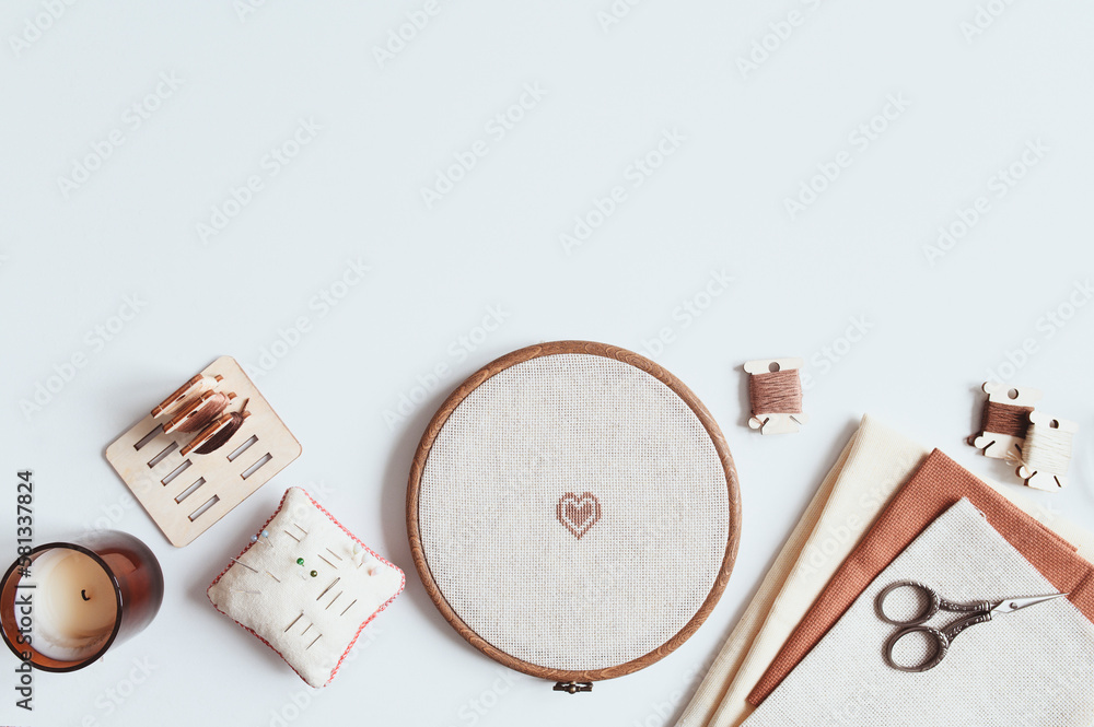 cross stitch embroidery accessories. Linen cloth in hoop on white  background with floss, scissors and cloth. Indoor hobby concept. Stock  Photo