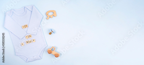 Baby bodysuit with lettering, with toys on a blue background. Concept baby, boy.