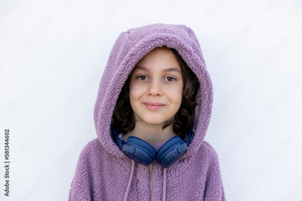 teenager in headphones and a purple hidi is standing on the street. Stylish boy. teenager in headphones and a purple hidi is standing on the street. Stylish boy.