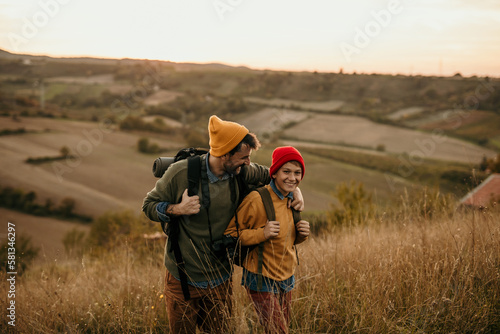 Image of a young father walking and talking with his teenage son in an autumn field, exploring and having fun.