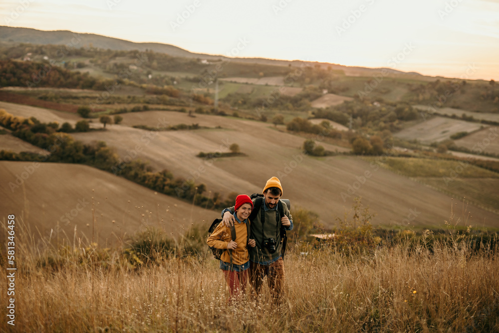 Obraz premium A mid adult father walking and talking with his teenage son in an autumn field, exploring and having fun.