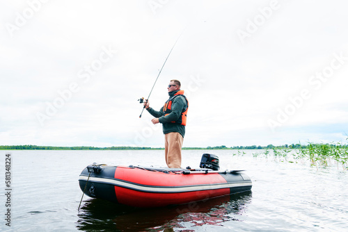 A thirty-year-old man in glasses and a safety vest catches a fish from a boat